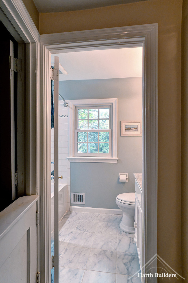 Inspiration for a small rural bathroom in Philadelphia with recessed-panel cabinets, white cabinets, a built-in bath, a shower/bath combination, a two-piece toilet, white tiles, porcelain tiles, blue walls, marble flooring, a submerged sink and marble worktops.