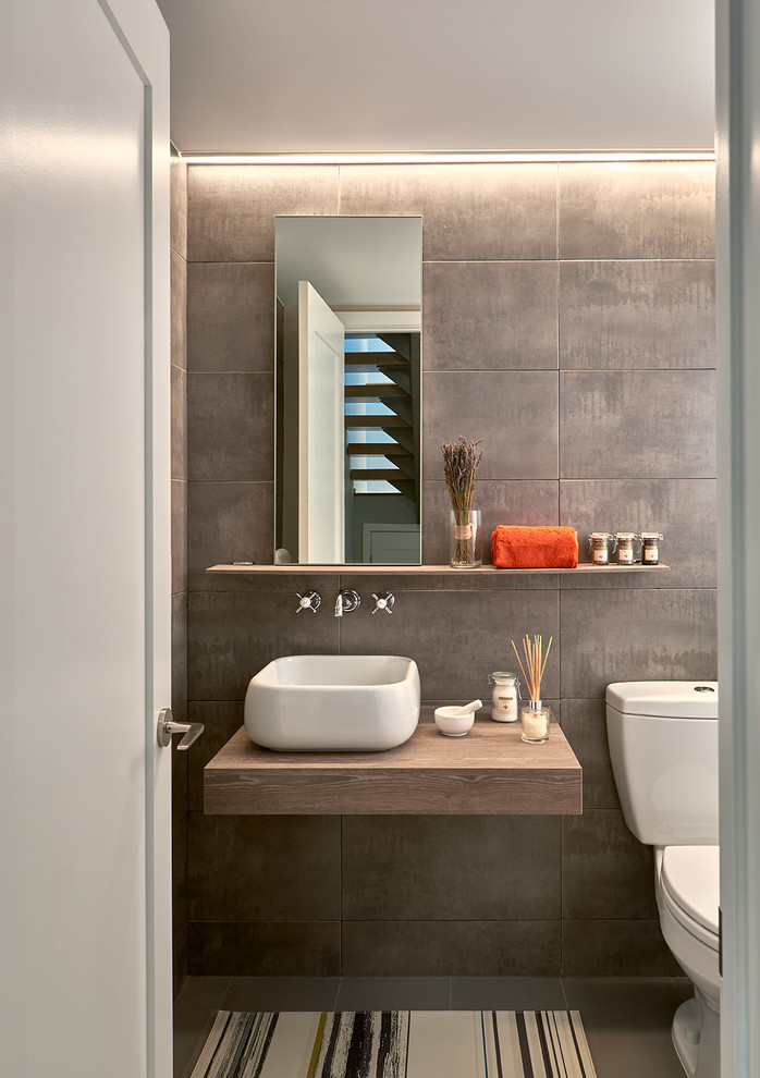 На фото: ванная комната в современном стиле с плоскими фасадами, коричневыми стенами и настольной раковиной с