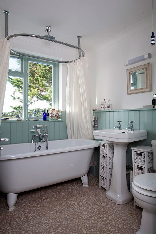 Bild på ett litet maritimt badrum för barn, med ett fristående badkar, en dusch/badkar-kombination, en toalettstol med hel cisternkåpa, grå kakel, keramikplattor, vita väggar, klinkergolv i småsten, ett integrerad handfat och marmorbänkskiva