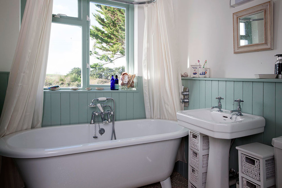 Cette photo montre une petite salle de bain bord de mer avec une baignoire indépendante, un combiné douche/baignoire, WC à poser, un carrelage gris, des carreaux de céramique, un mur blanc, un sol en galet, un lavabo intégré et un plan de toilette en marbre.