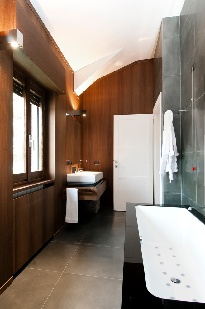 Inspiration pour une salle de bain design avec une vasque, un carrelage gris, une baignoire d'angle et une fenêtre.