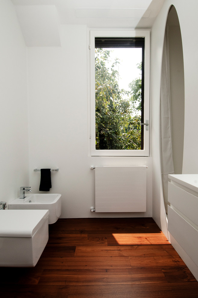 Design ideas for a contemporary bathroom in Milan with an alcove shower, a bidet, flat-panel cabinets, white cabinets, white walls and dark hardwood flooring.