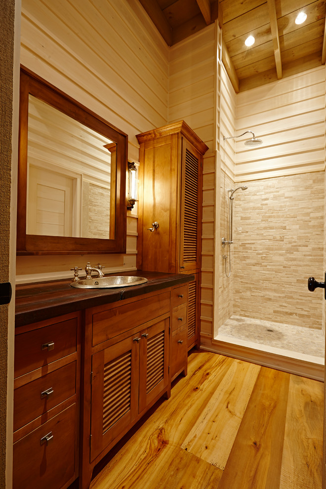 Exemple d'une salle de bain montagne en bois foncé de taille moyenne avec un lavabo posé, un placard à porte persienne, un plan de toilette en bois, une douche ouverte, un carrelage beige, un carrelage de pierre, un mur beige et un sol en bois brun.