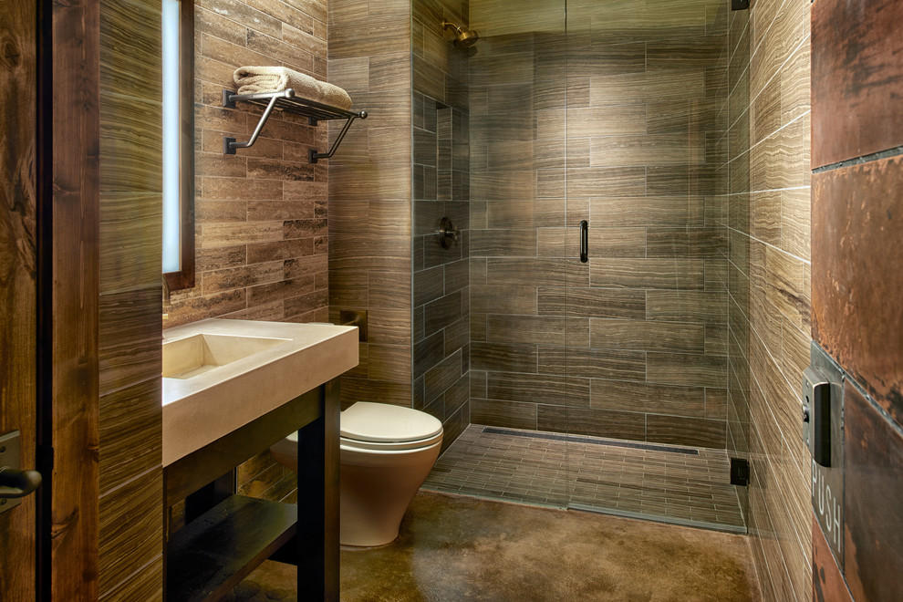 Medium sized rustic shower room bathroom in Denver with open cabinets, an alcove shower, a one-piece toilet, brown tiles, porcelain tiles, brown walls, concrete flooring, an integrated sink, brown floors and a hinged door.