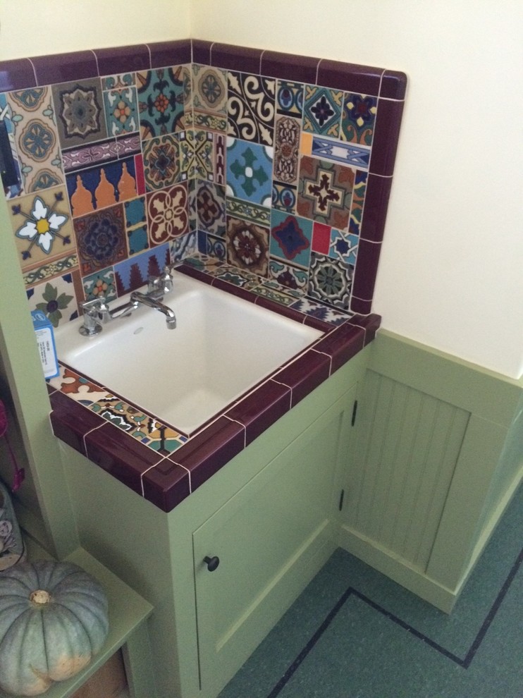 Cette image montre une salle de bain chalet avec des portes de placards vertess, des carreaux de céramique, un mur blanc et un carrelage multicolore.
