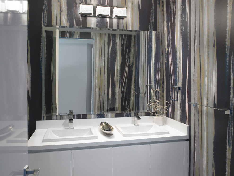 Imagen de cuarto de baño moderno de tamaño medio con armarios con paneles lisos, puertas de armario grises, sanitario de una pieza, paredes multicolor, aseo y ducha, lavabo encastrado, encimera de acrílico y encimeras blancas