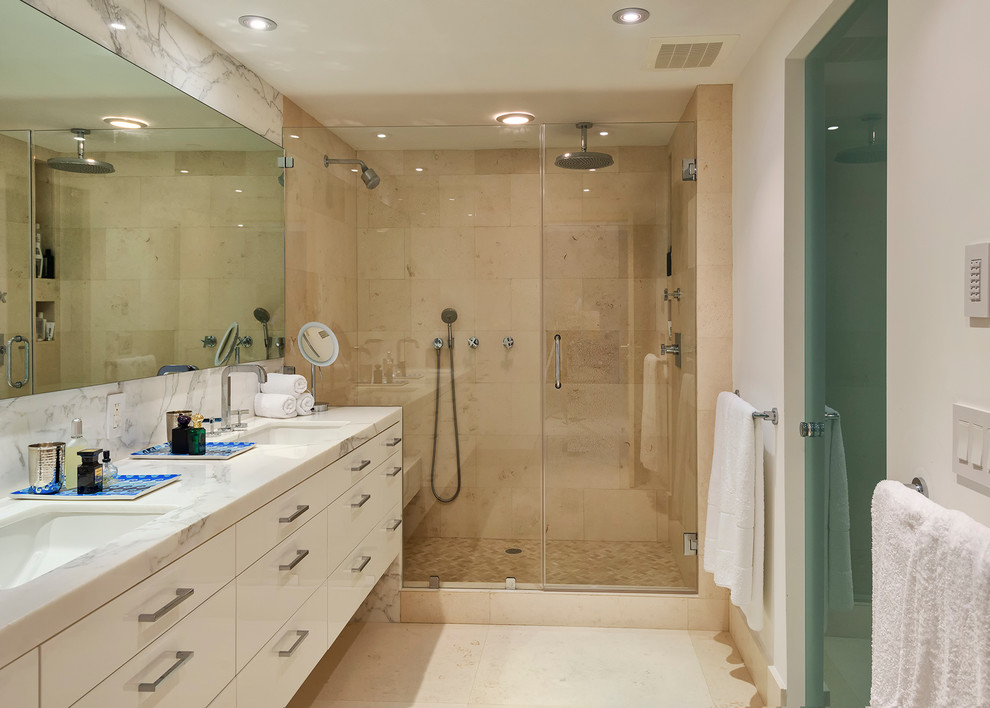 Modern inredning av ett stort en-suite badrum, med släta luckor, vita skåp, marmorbänkskiva, en dubbeldusch, beige kakel, stenkakel, vita väggar och kalkstensgolv