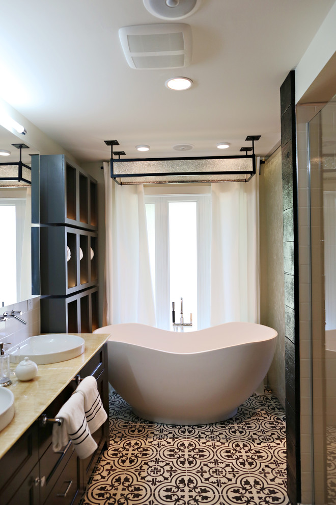 Стильный дизайн: главная ванная комната среднего размера в стиле неоклассика (современная классика) с настольной раковиной, фасадами с выступающей филенкой, темными деревянными фасадами, столешницей из оникса, отдельно стоящей ванной, душем в нише, унитазом-моноблоком, белой плиткой, керамической плиткой, белыми стенами и бетонным полом - последний тренд
