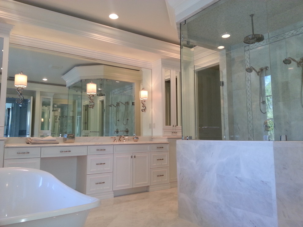 На фото: главная ванная комната в классическом стиле с фасадами с выступающей филенкой, белыми фасадами, отдельно стоящей ванной, угловым душем, бежевой плиткой, керамогранитной плиткой, белыми стенами и полом из керамогранита с