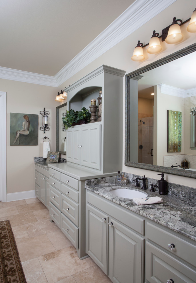 Foto de cuarto de baño principal tradicional de tamaño medio con armarios con paneles con relieve, puertas de armario grises, bañera esquinera, paredes beige y encimera de granito