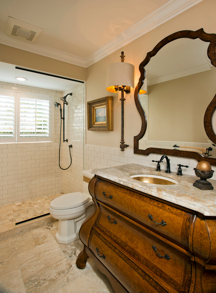 Inredning av ett klassiskt mellanstort en-suite badrum, med ett integrerad handfat, möbel-liknande, skåp i mellenmörkt trä, marmorbänkskiva, ett fristående badkar, en öppen dusch, vit kakel, stenhäll, beige väggar och klinkergolv i keramik