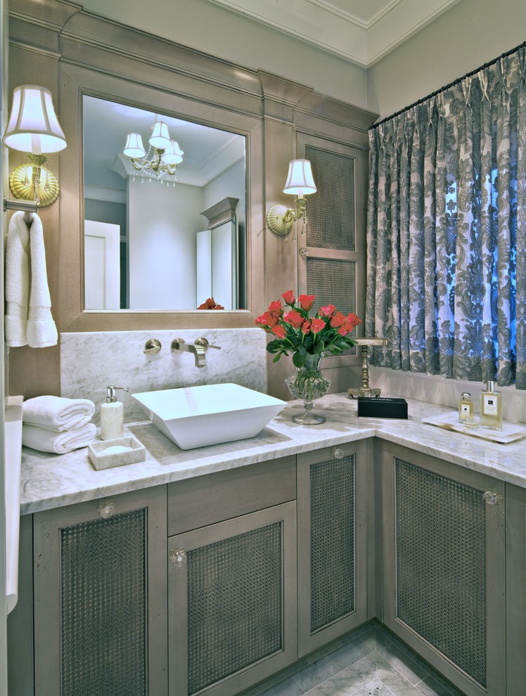 Cette photo montre une salle de bain chic de taille moyenne avec une vasque, un placard à porte plane, des portes de placard marrons, un mur gris et un plan de toilette en marbre.