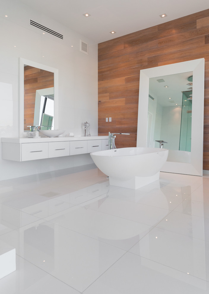 Exemple d'une salle de bain tendance avec un lavabo suspendu, un placard à porte plane, un plan de toilette en marbre, WC suspendus, un mur blanc et une baignoire indépendante.