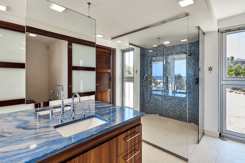 Cette photo montre une salle de bain principale moderne en bois brun de taille moyenne avec un placard à porte plane, une douche double, WC suspendus, un carrelage bleu, mosaïque, un mur blanc, un lavabo encastré, un plan de toilette en granite et un plan de toilette bleu.