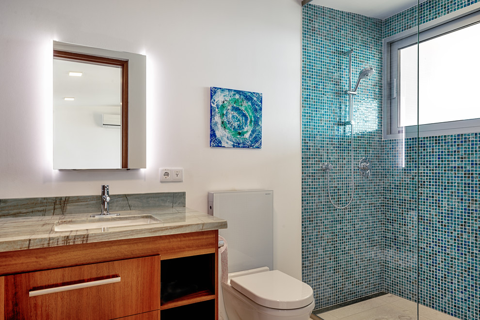 Idées déco pour une salle de bain principale moderne en bois brun de taille moyenne avec un placard à porte plane, une douche ouverte, WC suspendus, un carrelage bleu, mosaïque, un mur blanc, un lavabo encastré, un plan de toilette en granite et un plan de toilette vert.