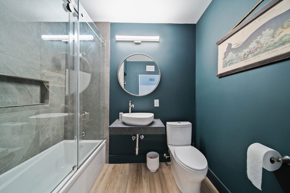 Exemple d'une salle de bain principale tendance de taille moyenne avec des portes de placard grises, une baignoire en alcôve, WC séparés, un carrelage gris, une vasque, un plan de toilette en granite, meuble simple vasque et meuble-lavabo suspendu.