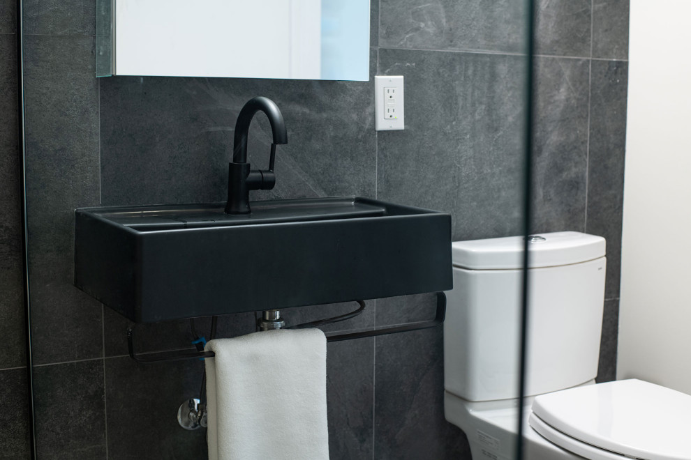 Inspiration pour une salle de bain principale design de taille moyenne avec des portes de placard noires, WC séparés, un carrelage gris, un lavabo suspendu, meuble simple vasque et meuble-lavabo suspendu.