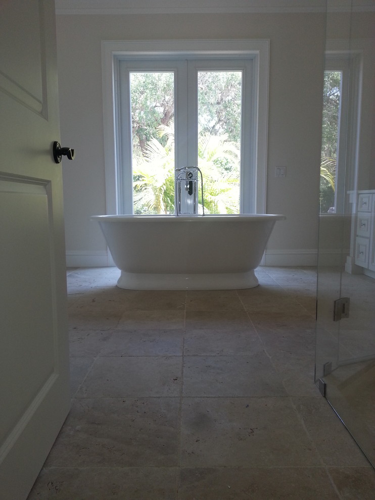 Foto de cuarto de baño principal marinero de tamaño medio con bañera exenta, baldosas y/o azulejos de piedra y suelo de travertino