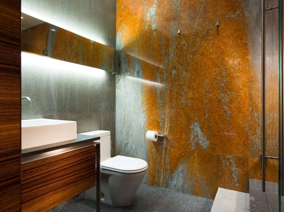 Kleines Modernes Duschbad mit flächenbündigen Schrankfronten, hellbraunen Holzschränken, grünen Fliesen, orangen Fliesen, grüner Wandfarbe, Aufsatzwaschbecken, grauem Boden, schwarzer Waschtischplatte und Toilette mit Aufsatzspülkasten in Miami
