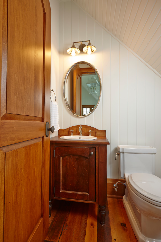 Inredning av ett rustikt litet badrum med dusch, med ett nedsänkt handfat, möbel-liknande, skåp i mörkt trä, träbänkskiva, en toalettstol med hel cisternkåpa, vita väggar och mellanmörkt trägolv
