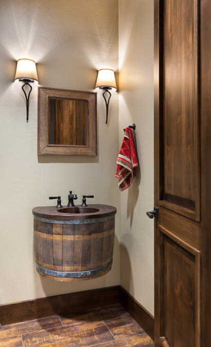 Bild på ett litet rustikt toalett, med ett piedestal handfat, skåp i shakerstil, skåp i mellenmörkt trä, träbänkskiva, en toalettstol med hel cisternkåpa, flerfärgad kakel, stenhäll, beige väggar och mörkt trägolv