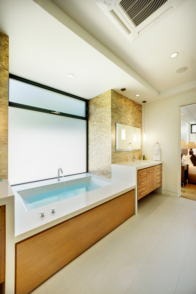 Aménagement d'une salle de bain contemporaine en bois clair avec un lavabo encastré, un placard à porte plane, une baignoire en alcôve et un carrelage beige.