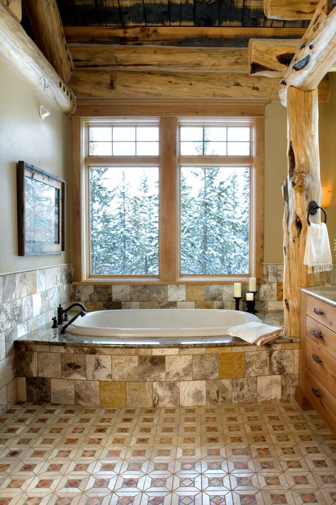 Photo of a rustic bathroom in Other with flat-panel cabinets, medium wood cabinets, granite worktops, a built-in bath, a walk-in shower, multi-coloured tiles and stone tiles.