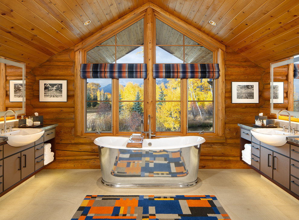 На фото: большая главная ванная комната в деревянном доме в стиле рустика с отдельно стоящей ванной, плоскими фасадами, коричневыми фасадами, коричневыми стенами, мраморной столешницей и полом из известняка