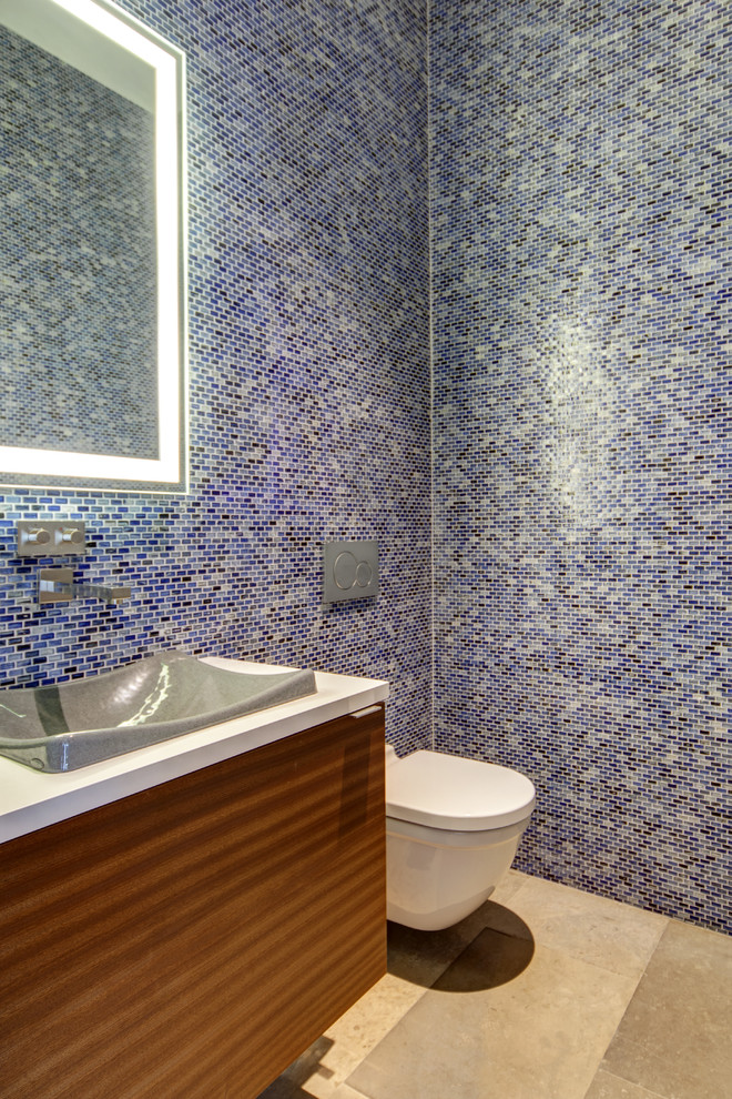ダラスにあるコンテンポラリースタイルのおしゃれなバスルーム (浴槽なし) (中間色木目調キャビネット、青いタイル、オーバーカウンターシンク、フラットパネル扉のキャビネット、壁掛け式トイレ、モザイクタイル) の写真