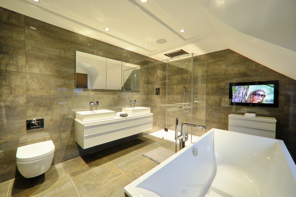Foto de cuarto de baño contemporáneo con lavabo sobreencimera, armarios con paneles lisos, puertas de armario blancas, bañera exenta, ducha esquinera, sanitario de pared y baldosas y/o azulejos marrones