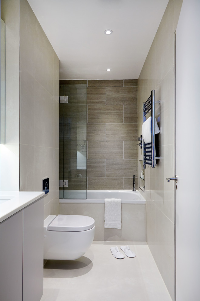 Inspiration for a contemporary master beige tile and ceramic tile ceramic tile drop-in bathtub remodel in London with flat-panel cabinets, a wall-mount toilet, beige walls, an undermount sink and solid surface countertops