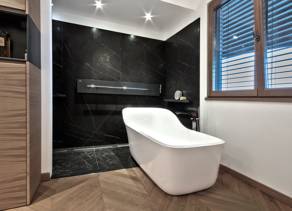 Idée de décoration pour une grande salle de bain principale design en bois clair avec un placard à porte plane, une baignoire indépendante, une douche à l'italienne, WC suspendus, un carrelage noir, des dalles de pierre, un mur blanc, parquet clair, une vasque et un plan de toilette en marbre.