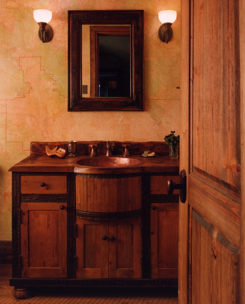 Rustik inredning av ett badrum, med luckor med infälld panel, mellanmörkt trägolv, ett nedsänkt handfat och träbänkskiva