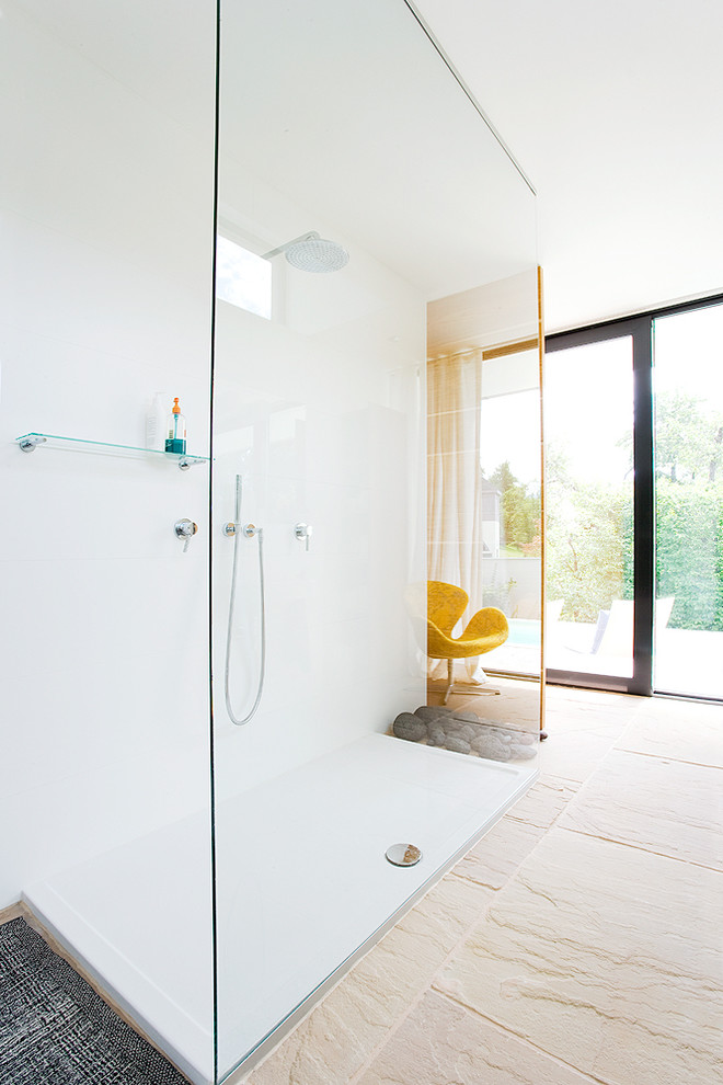 Modelo de cuarto de baño moderno grande con ducha abierta, paredes blancas, suelo de travertino y ducha abierta