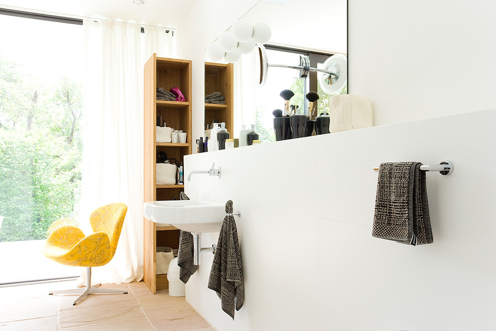 Пример оригинального дизайна: ванная комната среднего размера: освещение в стиле модернизм с подвесной раковиной, белыми стенами и полом из травертина