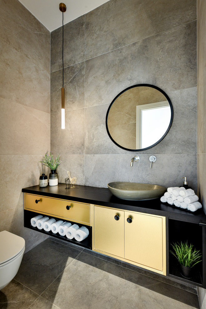 Пример оригинального дизайна: ванная комната среднего размера в современном стиле с плоскими фасадами, желтыми фасадами, инсталляцией, серой плиткой, керамогранитной плиткой, полом из керамогранита, душевой кабиной, настольной раковиной, серым полом и черной столешницей