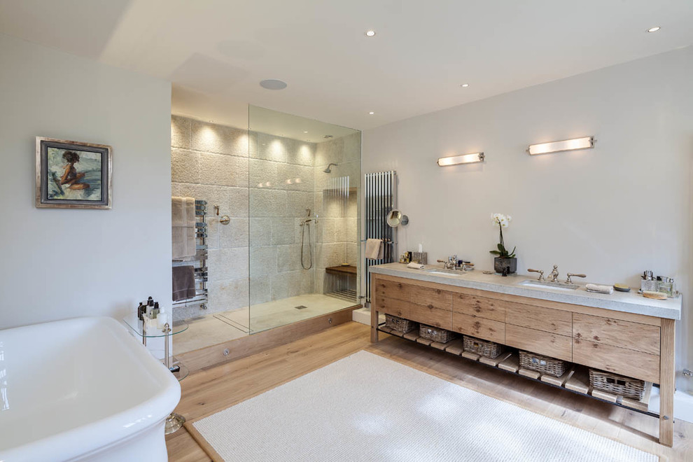 Modelo de cuarto de baño campestre con bañera exenta, ducha abierta, suelo de madera clara y ducha abierta