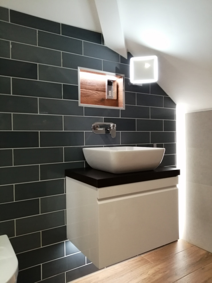 Cette image montre une petite salle de bain principale design avec des portes de placard blanches, un espace douche bain, WC suspendus, un carrelage gris, des carreaux de céramique, un mur gris, un sol en carrelage de porcelaine, un sol marron, une niche, meuble simple vasque et meuble-lavabo suspendu.