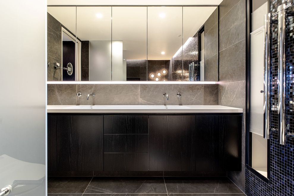 Свежая идея для дизайна: ванная комната в современном стиле с плоскими фасадами, темными деревянными фасадами, серой плиткой, серыми стенами, монолитной раковиной, серым полом и белой столешницей - отличное фото интерьера