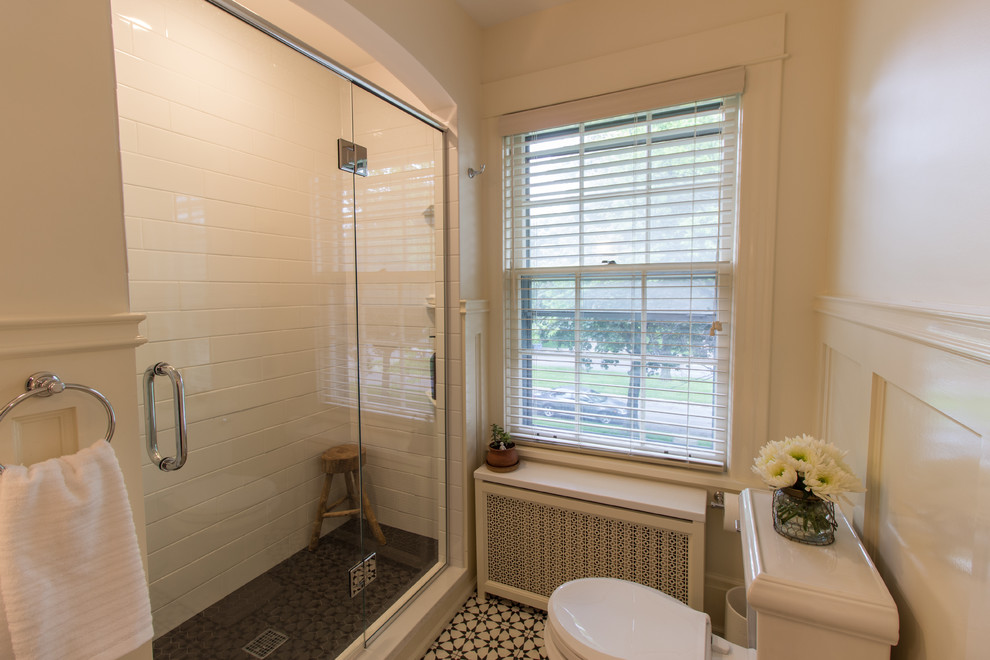 Exemple d'une douche en alcôve principale chic avec WC à poser, un carrelage blanc, un carrelage métro, un mur blanc, carreaux de ciment au sol, un plan vasque et une cabine de douche à porte battante.