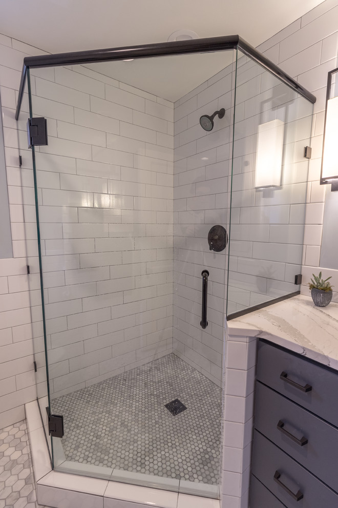 Large transitional master white tile and subway tile corner shower photo in Minneapolis with flat-panel cabinets, blue cabinets, a one-piece toilet, gray walls, an undermount sink, quartz countertops, a hinged shower door and beige countertops