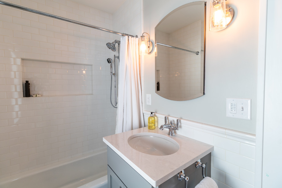 Пример оригинального дизайна: главная ванная комната среднего размера в классическом стиле с фасадами с утопленной филенкой, серыми фасадами, ванной в нише, душем в нише, унитазом-моноблоком, белой плиткой, плиткой кабанчик, серыми стенами, полом из керамогранита, врезной раковиной, столешницей из искусственного кварца, разноцветным полом, шторкой для ванной и белой столешницей