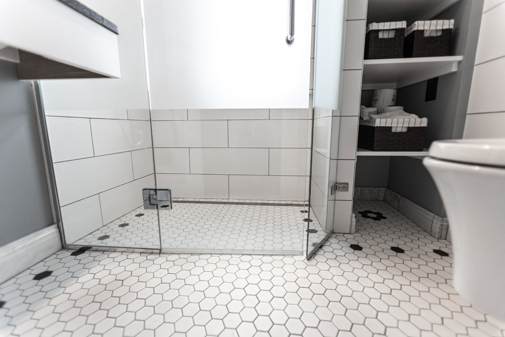 Bild på ett litet vintage grå grått badrum med dusch, med en kantlös dusch, en vägghängd toalettstol, vit kakel, keramikplattor, blå väggar, klinkergolv i porslin, ett undermonterad handfat, bänkskiva i återvunnet glas, vitt golv och dusch med gångjärnsdörr