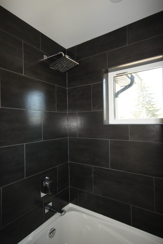 Modelo de cuarto de baño actual con lavabo bajoencimera, armarios con paneles lisos, puertas de armario de madera en tonos medios y baldosas y/o azulejos negros