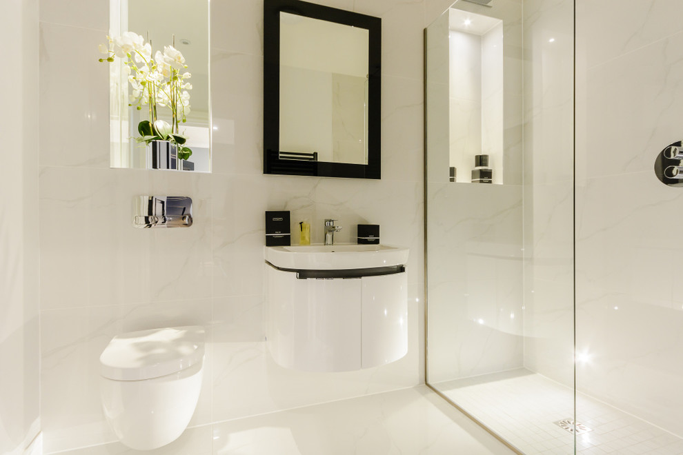 Modelo de cuarto de baño actual pequeño con ducha abierta, sanitario de pared, baldosas y/o azulejos de mármol, paredes blancas, suelo de mármol, lavabo suspendido, suelo blanco y ducha abierta