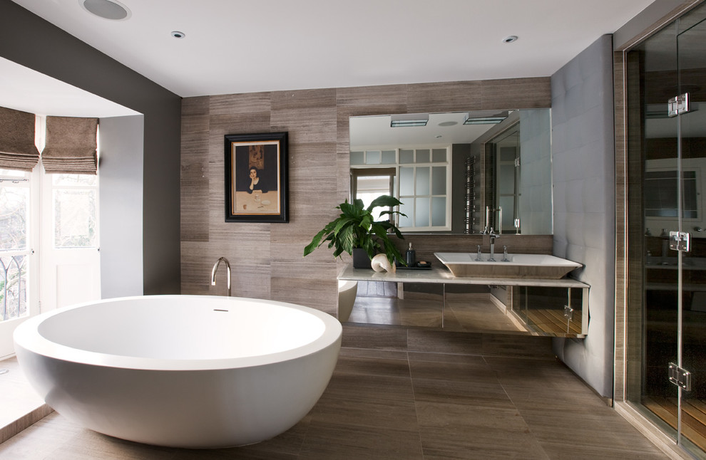 Пример оригинального дизайна: ванная комната в современном стиле с настольной раковиной, отдельно стоящей ванной, бежевой плиткой и серыми стенами