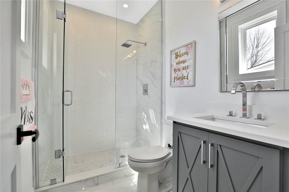 Inspiration for a large traditional family bathroom in Toronto with raised-panel cabinets, grey cabinets, a double shower, a one-piece toilet, grey tiles, marble tiles, white walls, marble flooring, a built-in sink, engineered stone worktops, grey floors and an open shower.