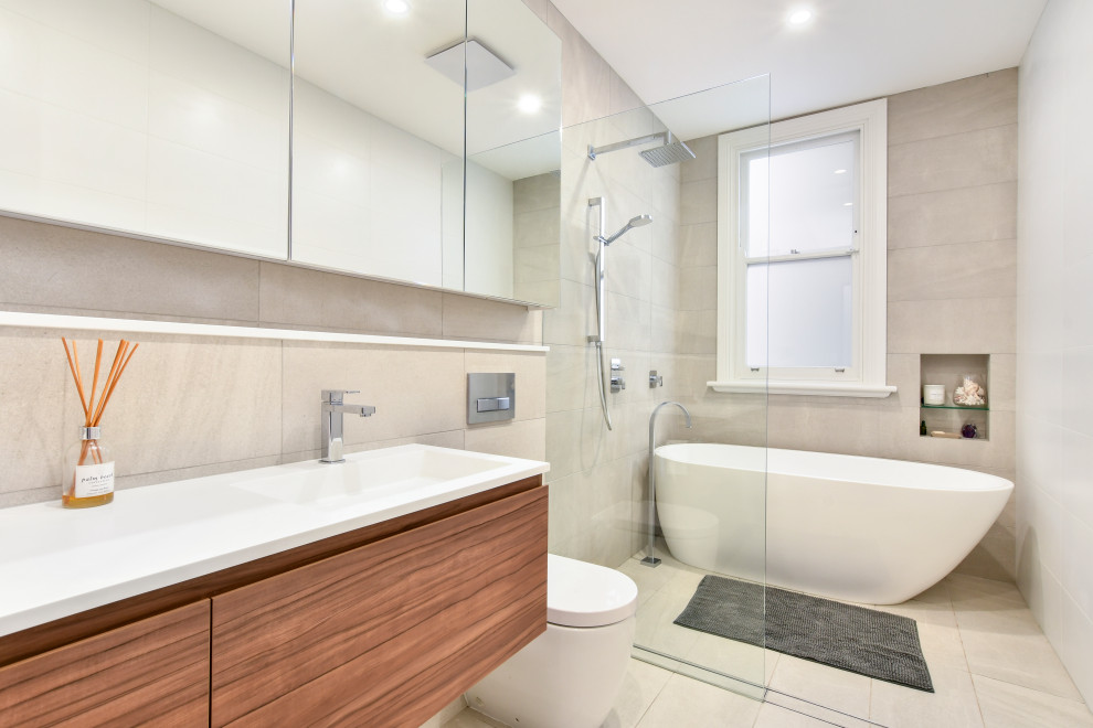 Inspiration for a contemporary bathroom in Sydney with flat-panel cabinets, a freestanding bath, a one-piece toilet, beige tiles, an integrated sink, beige floors, an open shower and white worktops.
