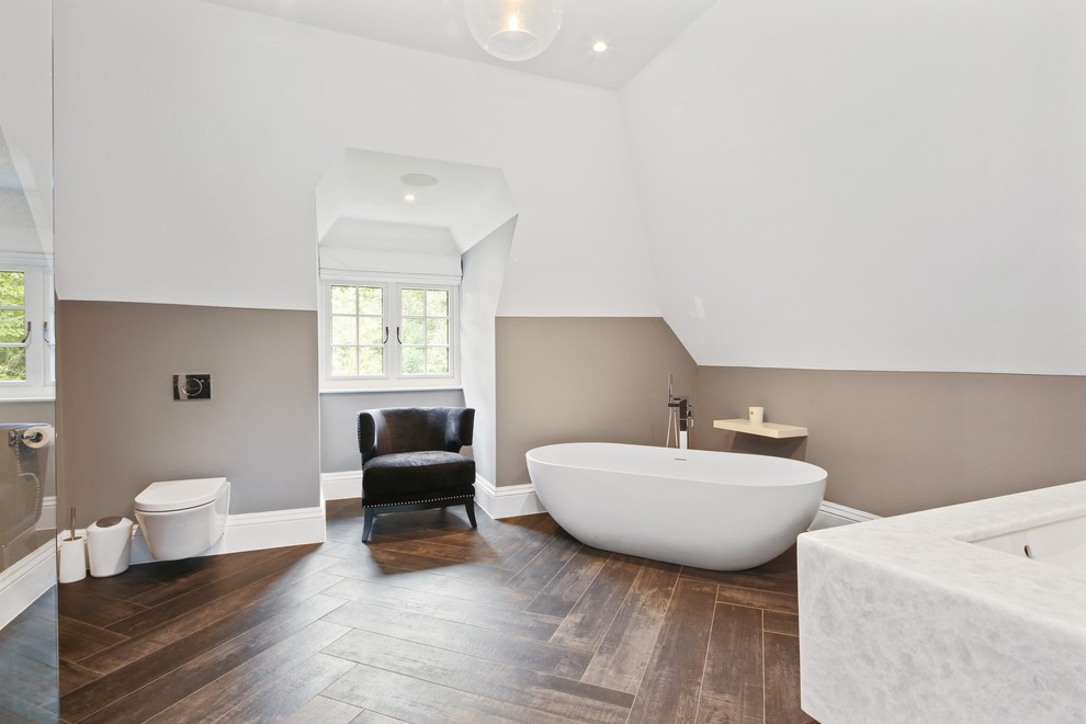 This is an example of a large contemporary family bathroom in Buckinghamshire with flat-panel cabinets, grey cabinets, a freestanding bath, a walk-in shower, a wall mounted toilet, white tiles, ceramic tiles, grey walls, ceramic flooring, an integrated sink, quartz worktops, brown floors and an open shower.