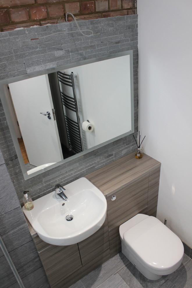 Example of a small trendy 3/4 gray tile and porcelain tile porcelain tile doorless shower design in London with a one-piece toilet, gray walls, a drop-in sink and laminate countertops